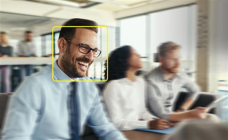 Male professional with yellow square around face in focus next to blurred colleagues