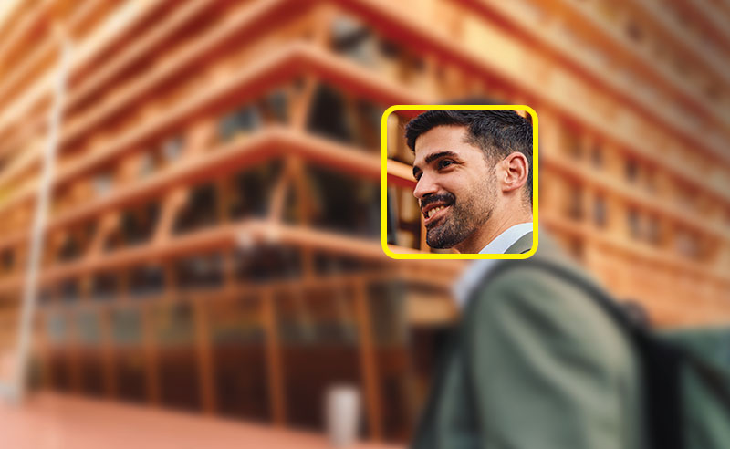 A young male professional in focus outside blurred building with yellow square around face.